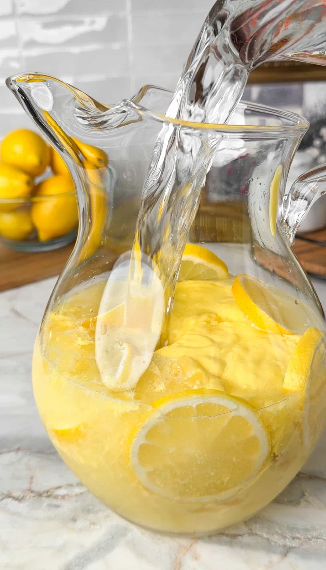 making mango lemonade in a pitcher
