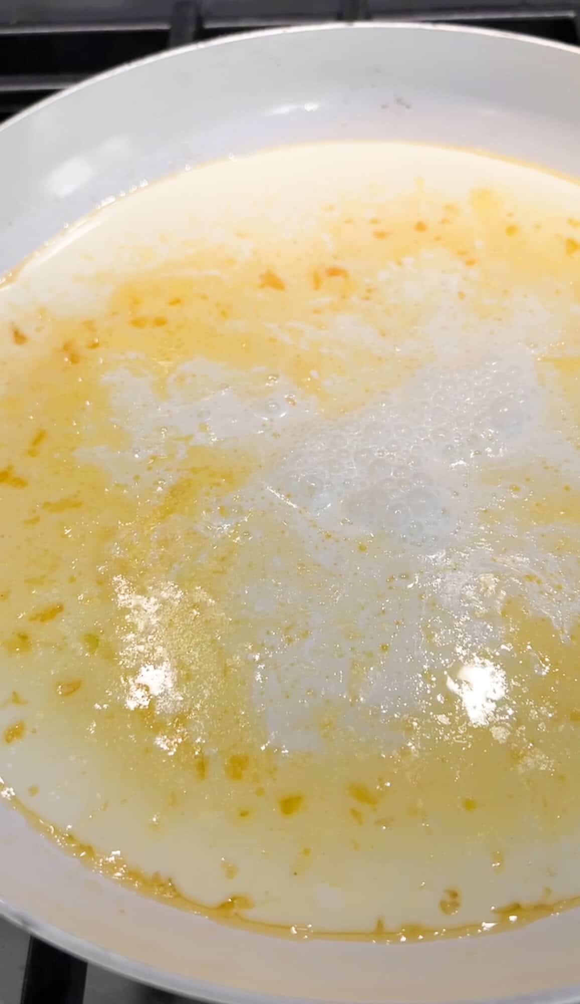 adding cream to alfredo sauce