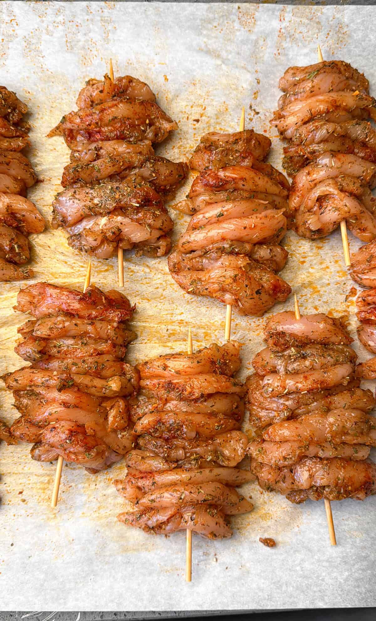 Season and Marinate the Chicken Greek marinated chicken loaded onto skewers.