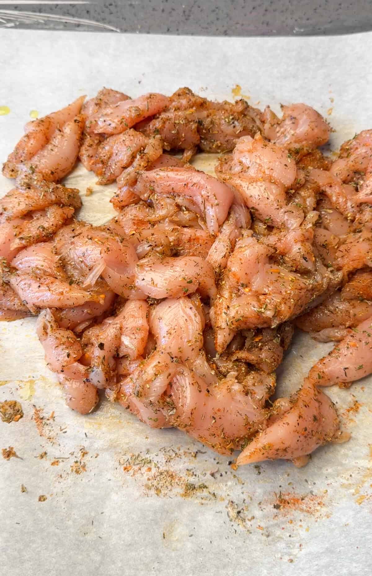 Season and Marinate the Chicken Sliced chicken marinating in smoked paprika, Greek seasoning, salt, and lemon juice.