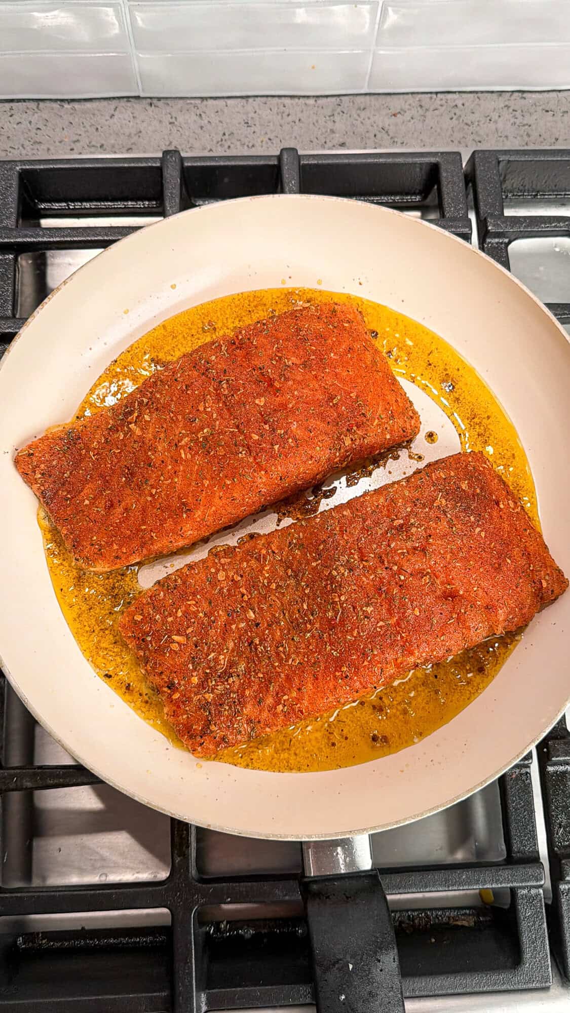 salmon seasoned with cajun seasoning cooking in a pan