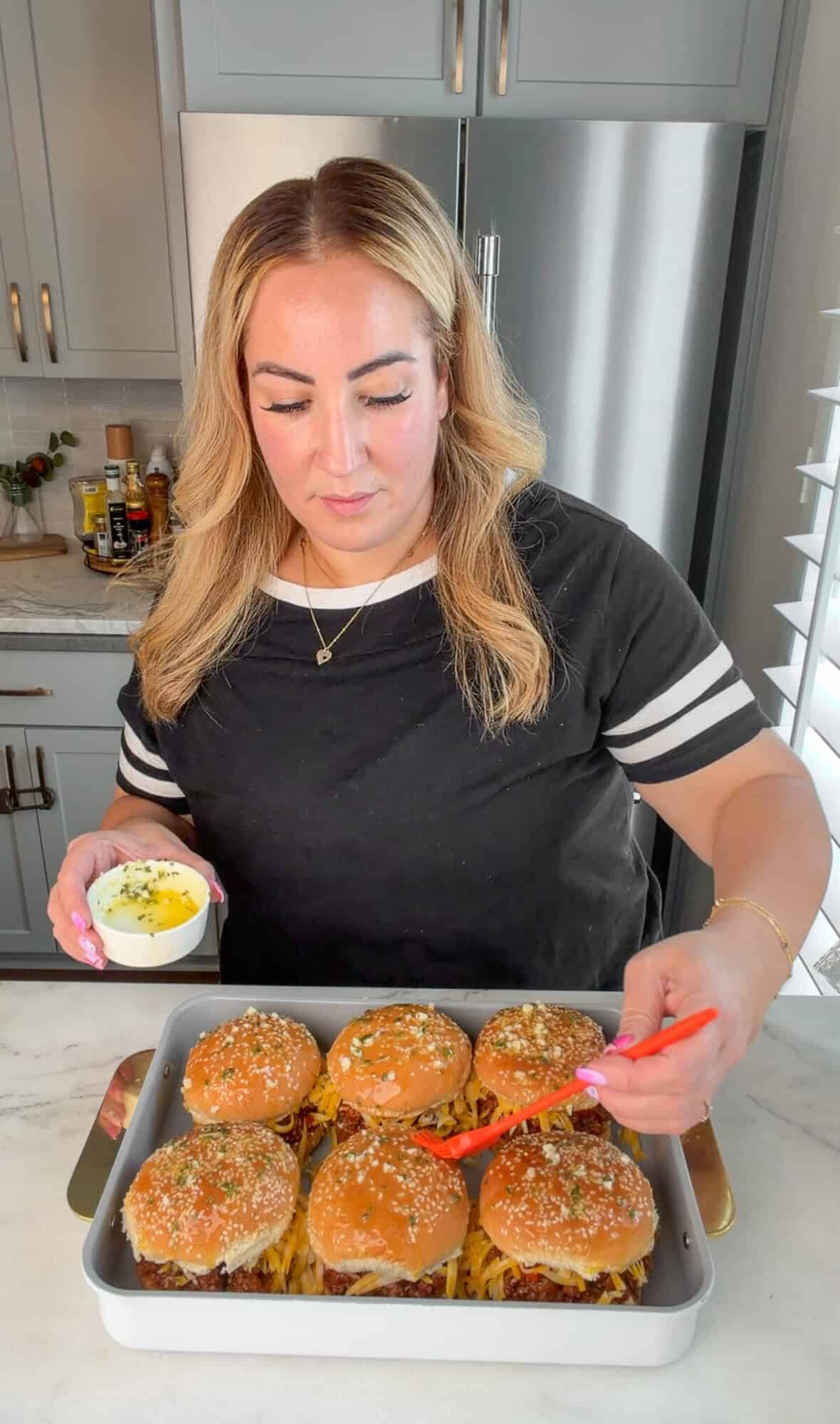 Mallory brushing sloppy Joes with garlic-parsley butter.
