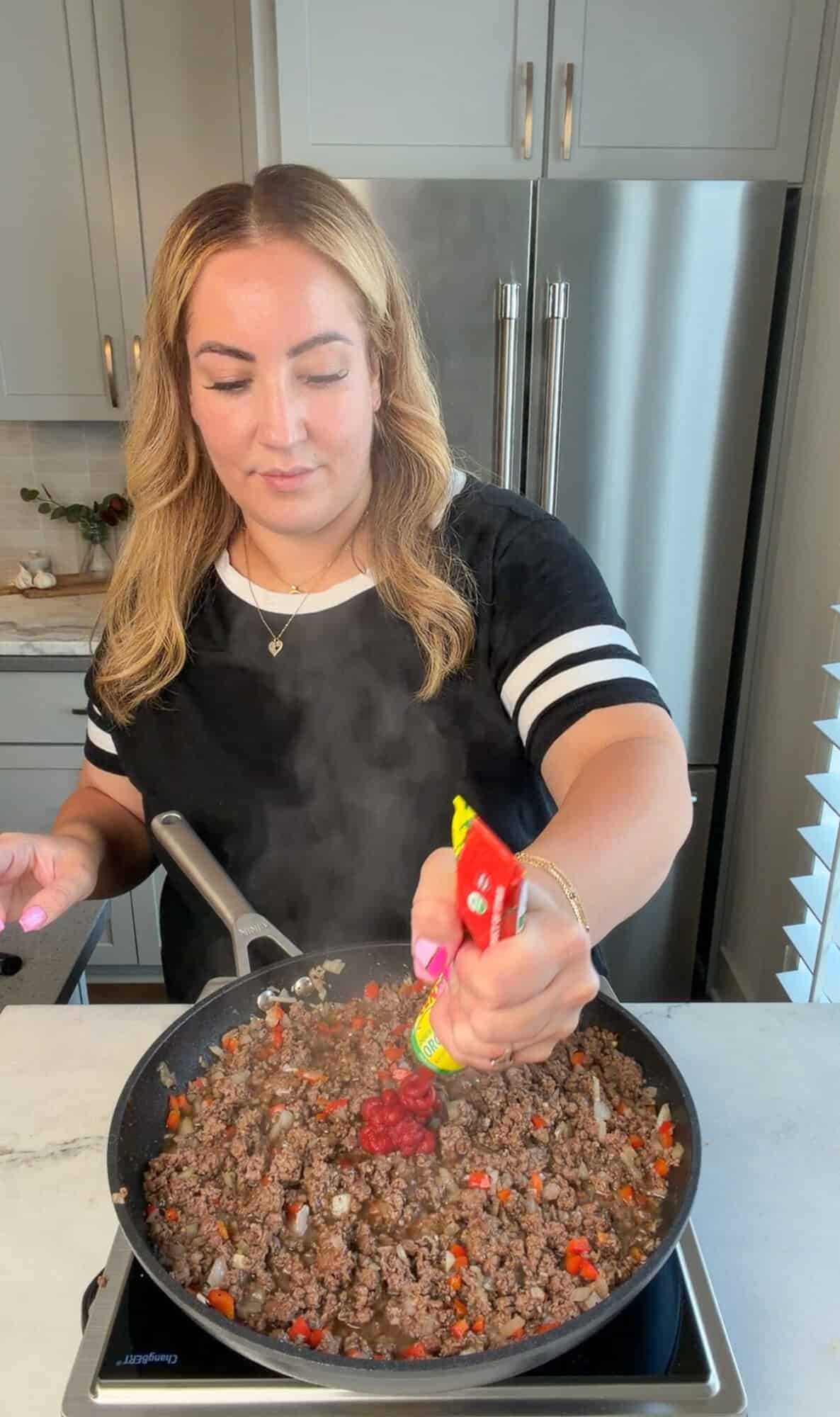 Adding tomato paste to homemade sloppy Joes filling.