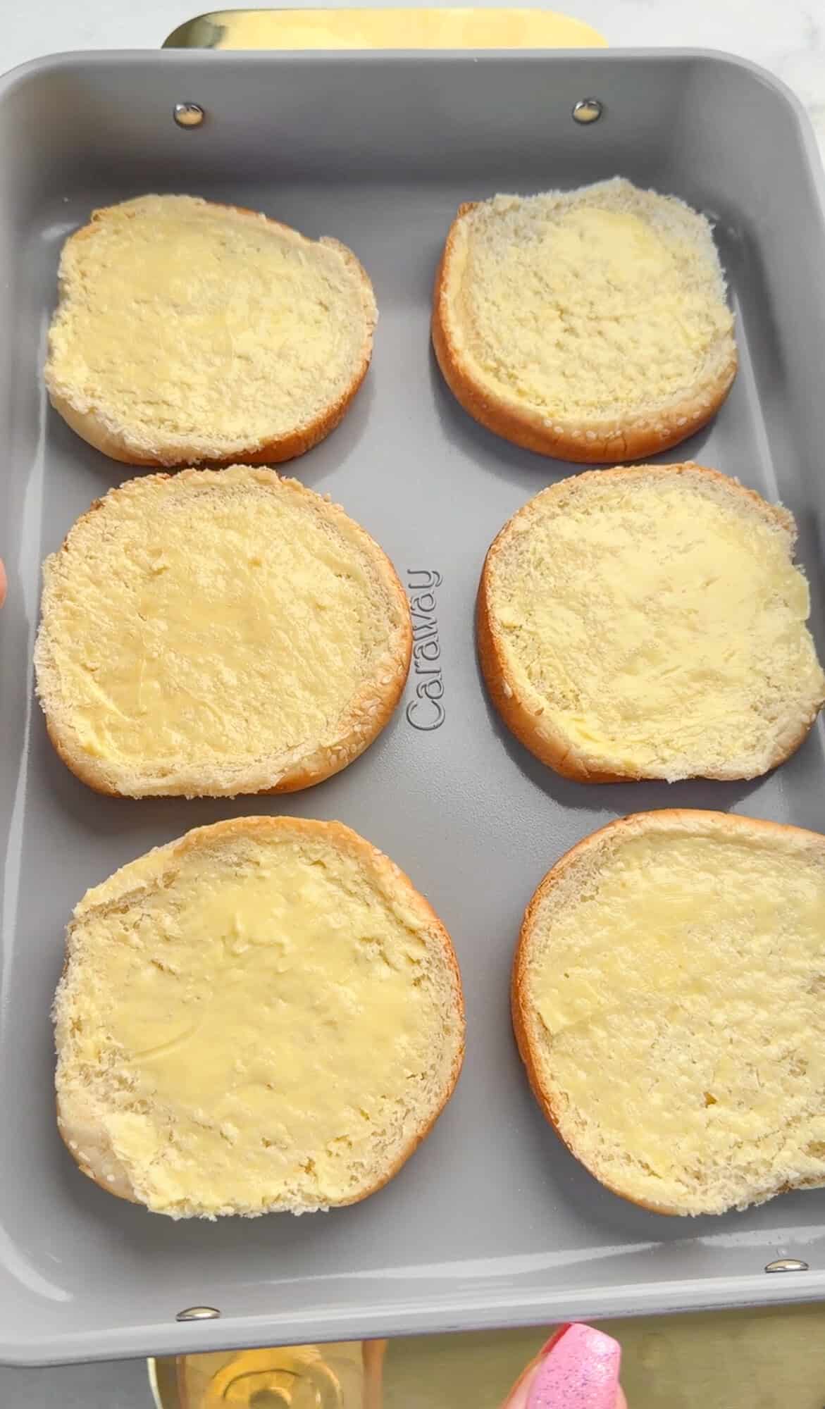 Buttered buns in a baking pan.