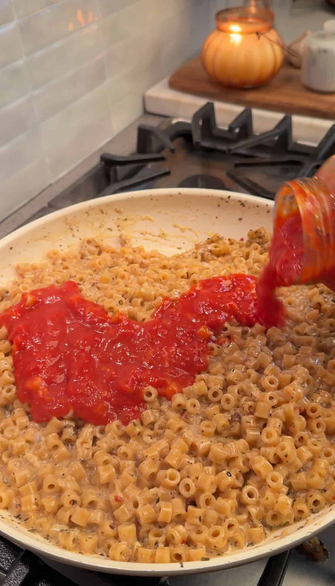 adding marinara sauce to meatball pasta