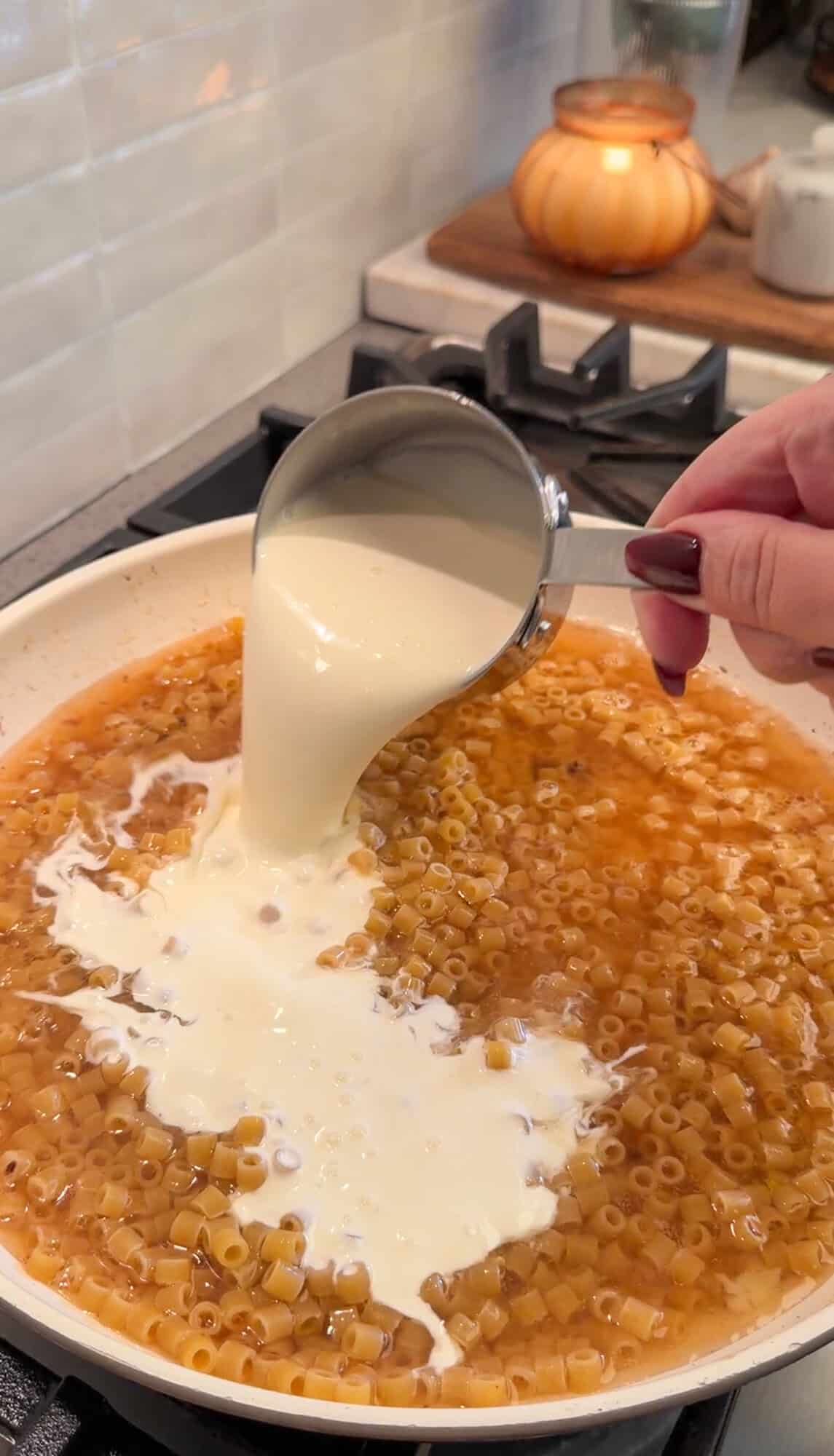 adding ingredients for one pan meatball pasta