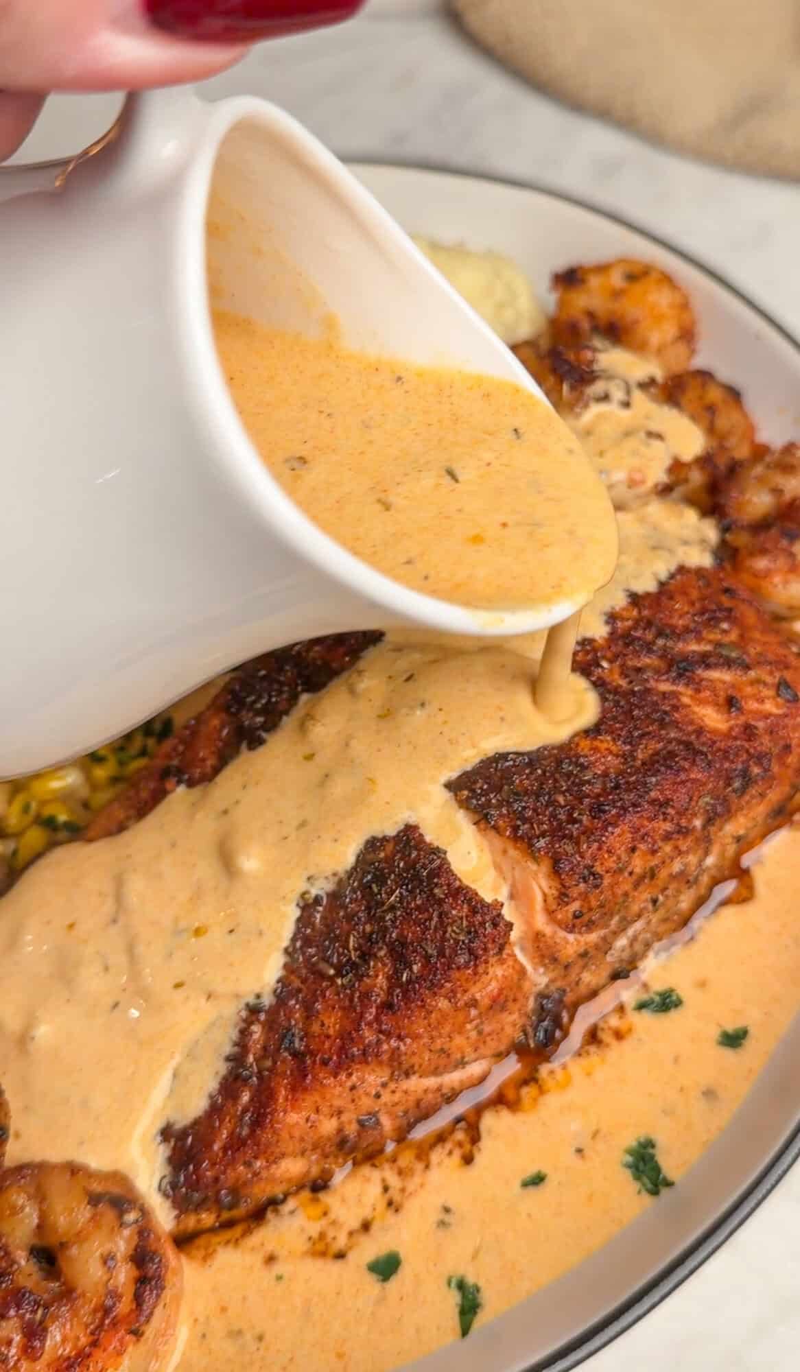 pouring cajun cream sauce on cajun salmon