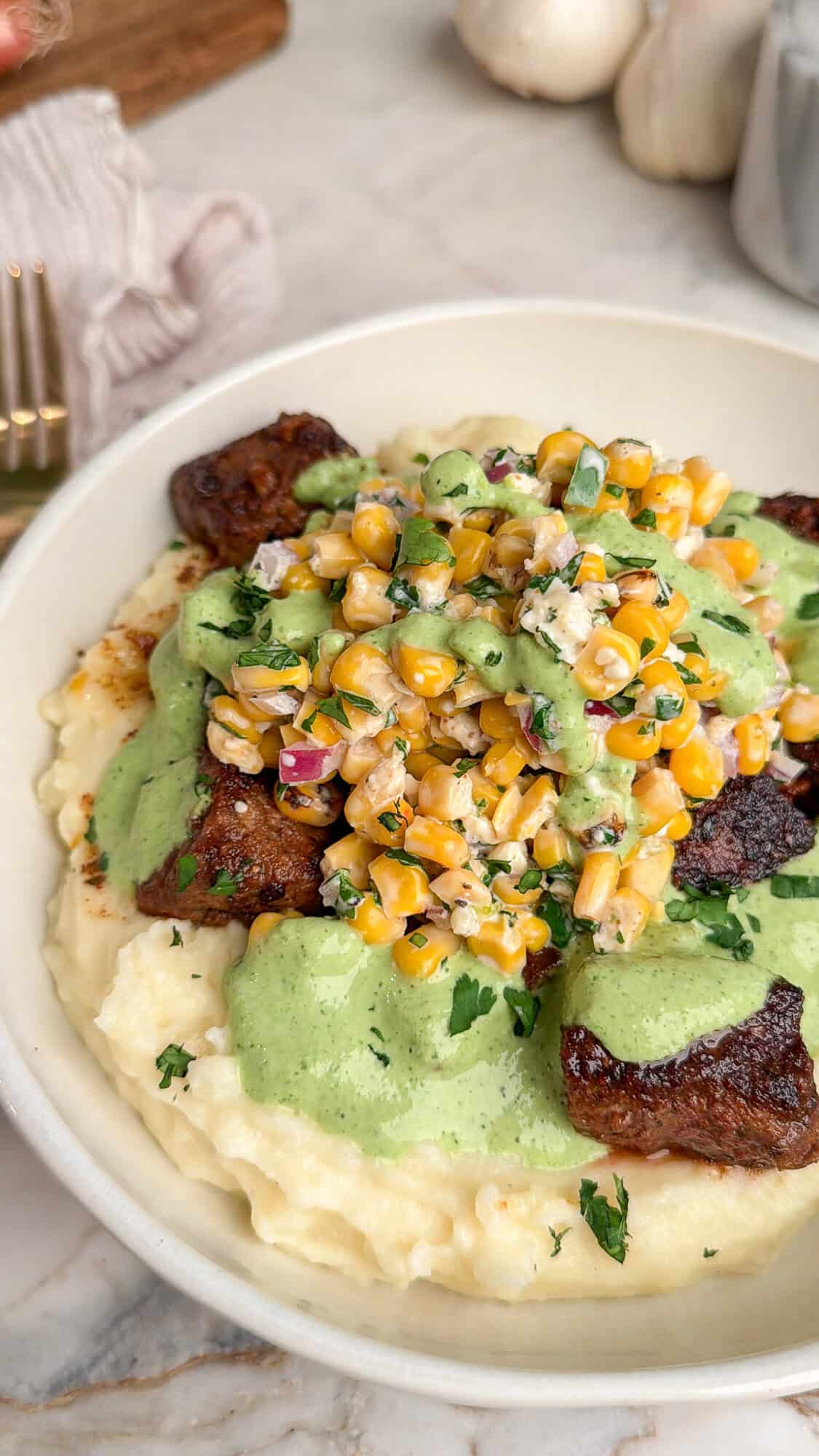 steak bowls topped with street corn on a bed of mashed potatoes