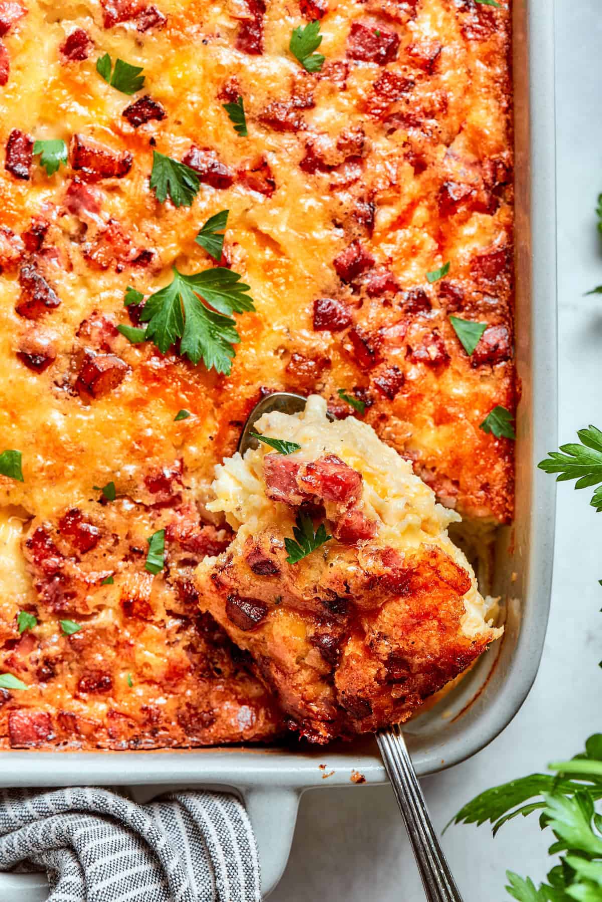 Loaded with bacon, eggs, and cheese and baked in one dish, this hashbrown breakfast casserole is the easiest way to do brunch for a crowd. A spatula reaching into hashbrown casserole to remove a slice.