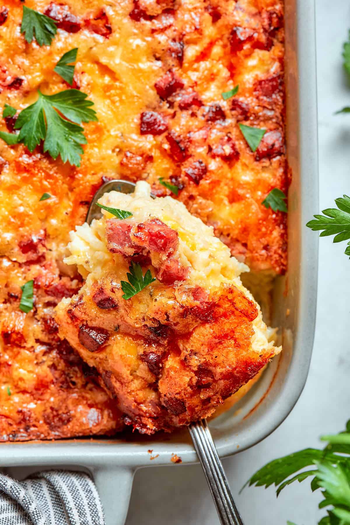 Loaded with bacon, eggs, and cheese and baked in one dish, this hashbrown breakfast casserole is the easiest way to do brunch for a crowd. A spatula reaching into hashbrown breakfast casserole to remove a slice.