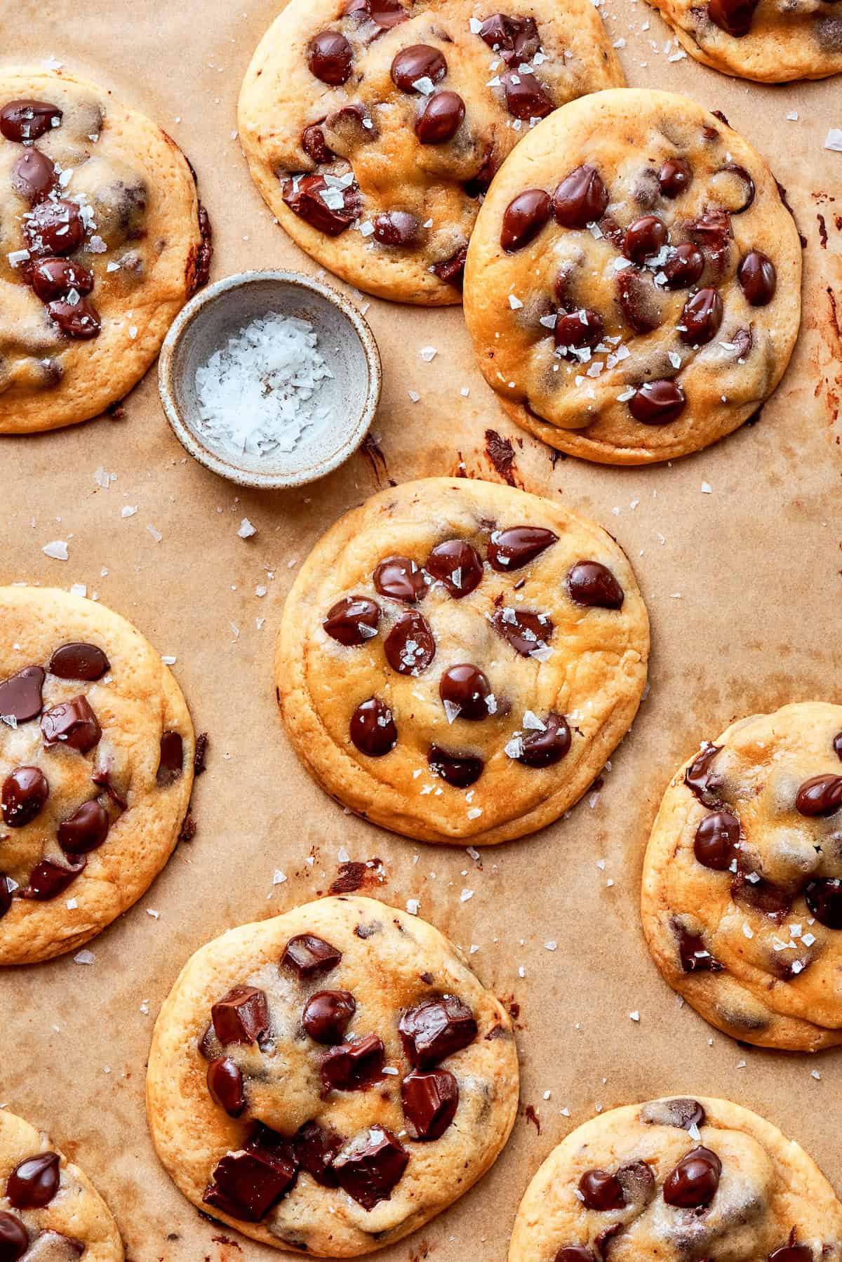Double dessert? Yes! These brownie-stuffed cookies wrap gooey brownie bites in chewy, golden-brown chocolate chip cookies. Overhead image of brownie stuffed chocolate chip cookies with a remekin of sea salt.