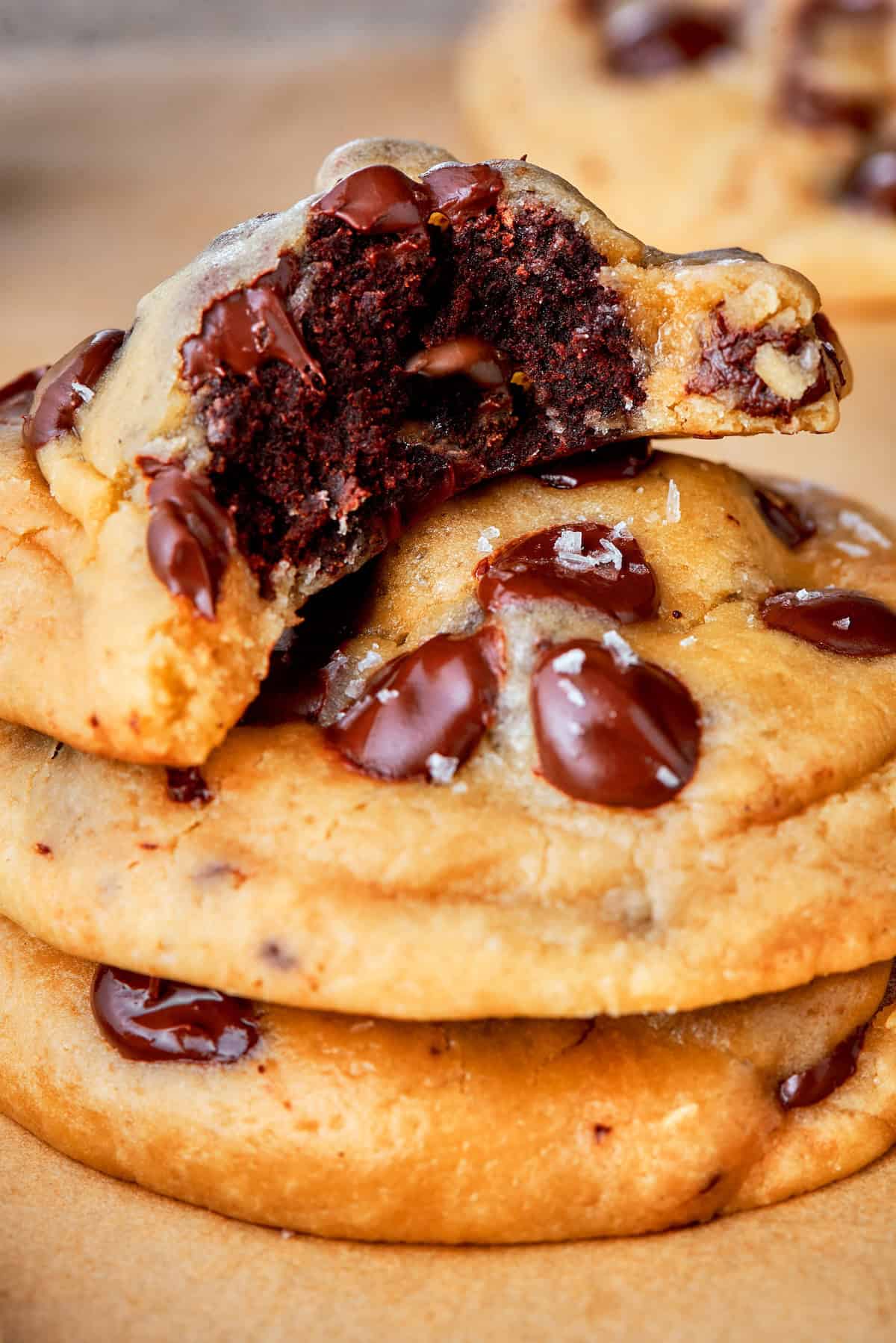 Double dessert? Yes! These brownie-stuffed cookies wrap gooey brownie bites in chewy, golden-brown chocolate chip cookies. Close-up of a stack of 3 stuffed cookies with the top one bitten into to reveal the brownie inside.