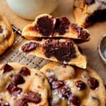A halved brownie-stuffed chocolate chip cookie stacked on whole cookies.