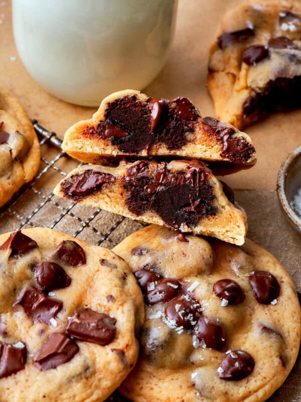A halved brownie-stuffed chocolate chip cookie stacked on whole cookies.