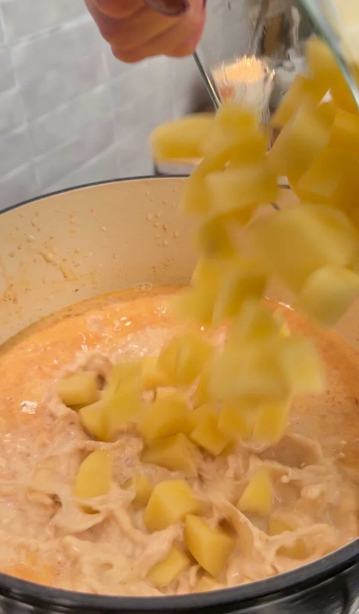 adding diced potatoes to loaded baked potato soup