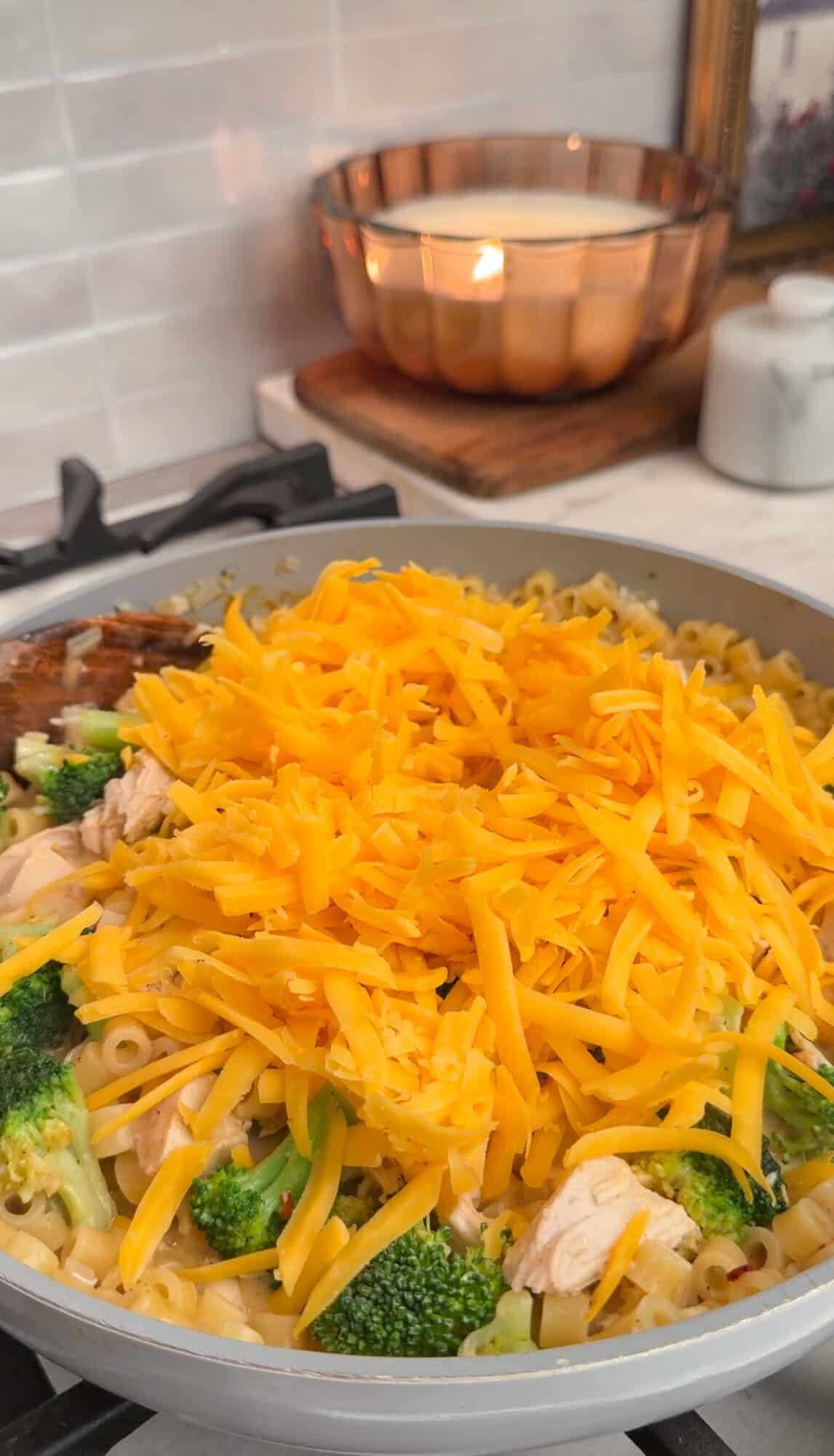 adding shredded cheddar to the pasta