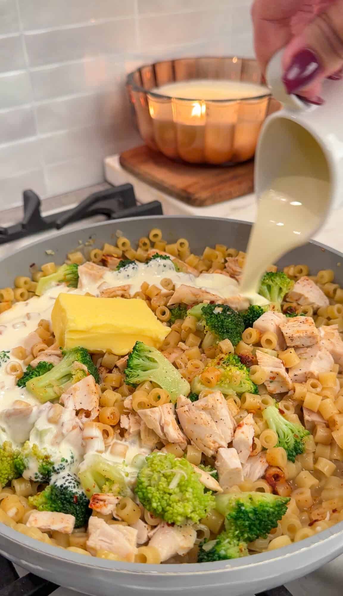 pouring cream and adding butter into the pasta to make the sauce