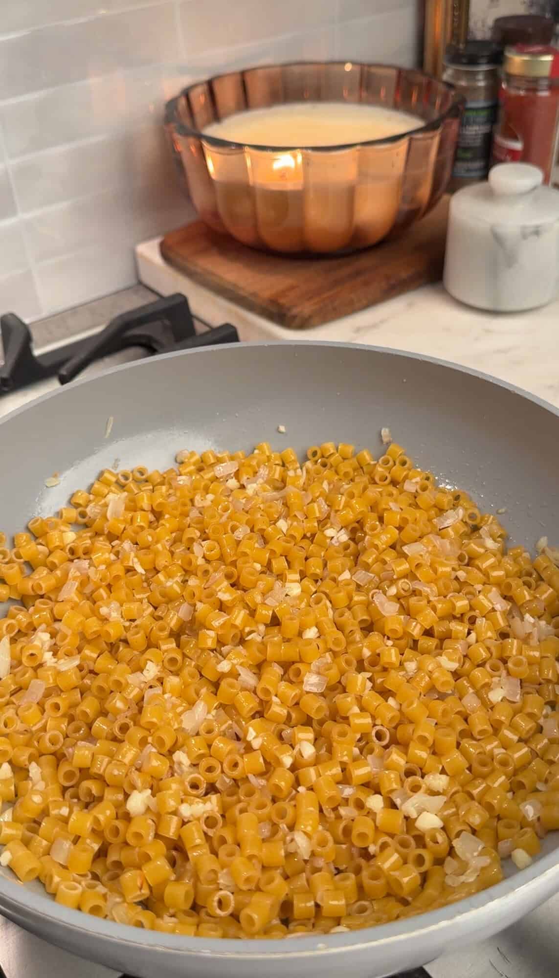 adding pasta to sauted garlic and shallots for broccoli cheddar pasta