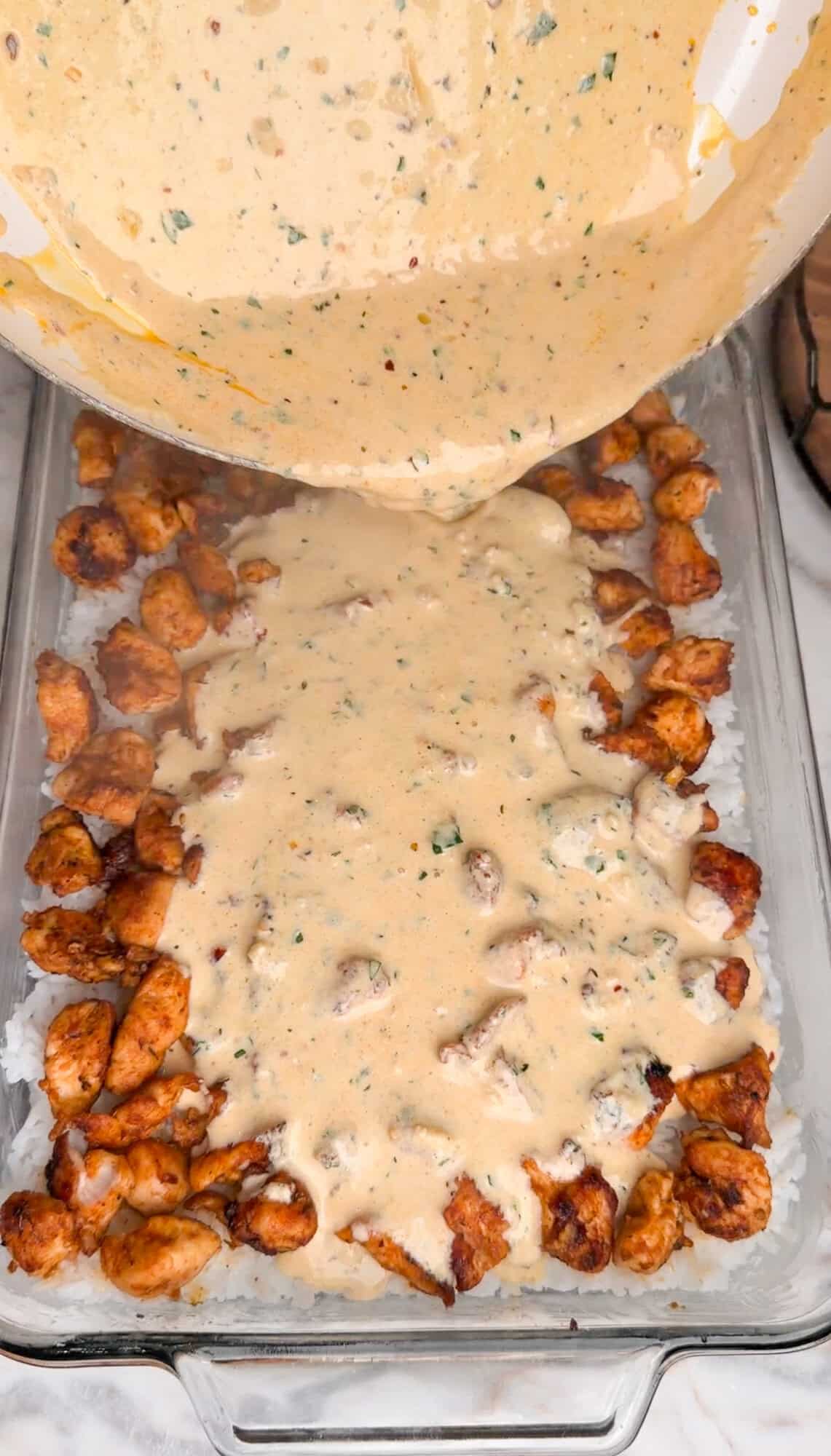 adding cream sauce to the cheesy chicken and rice bake