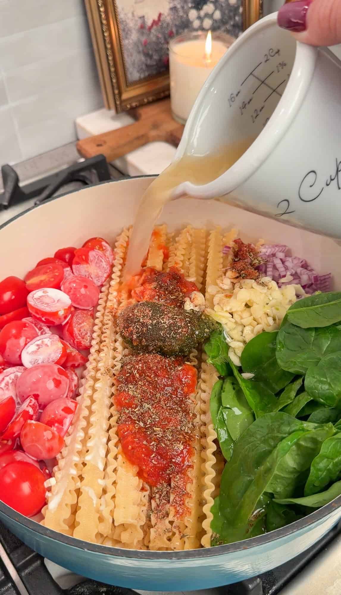 pouring in the chicken stock for creamy tomato pasta