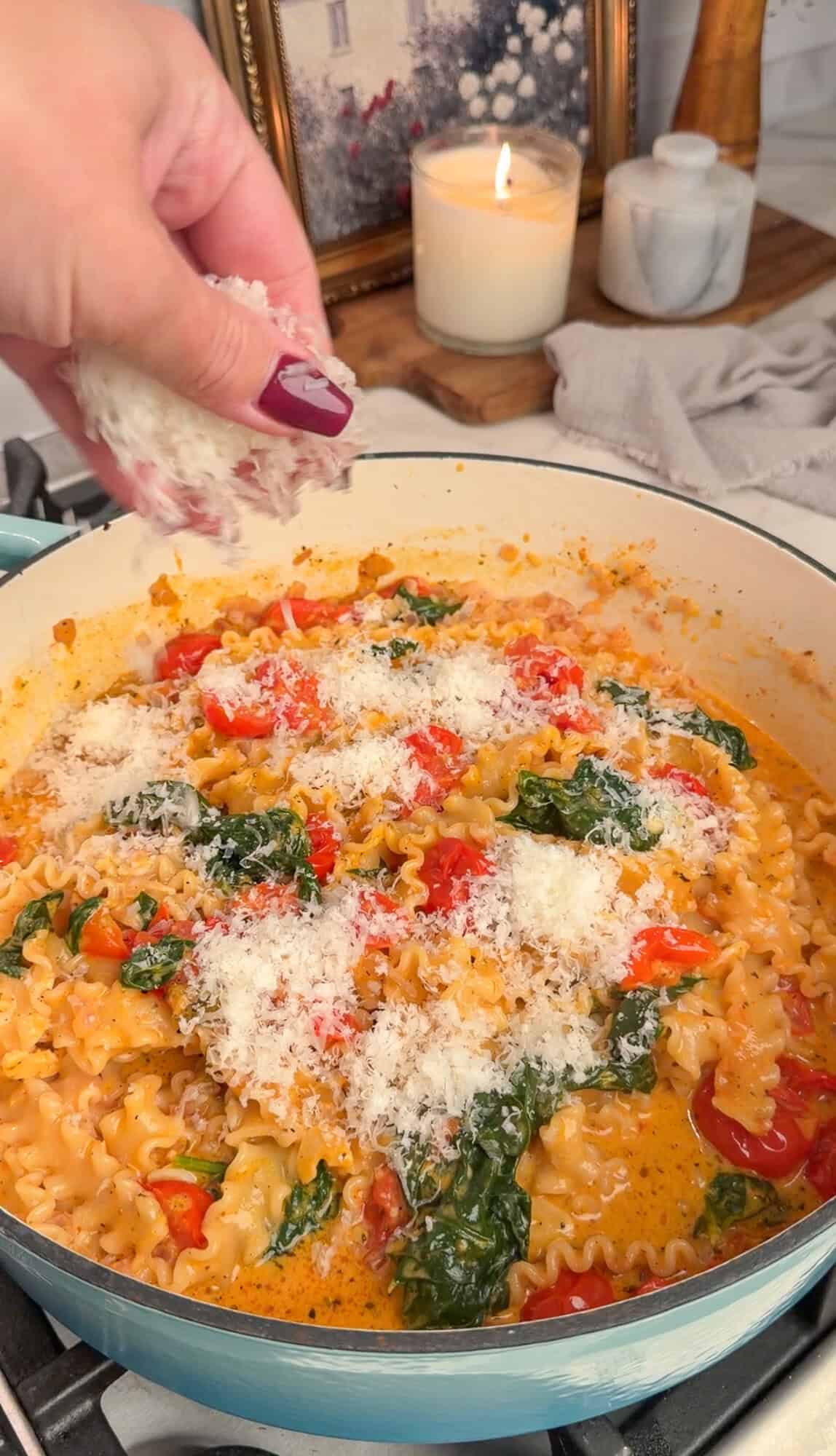 adding parmesan to the creamy tomato pasta