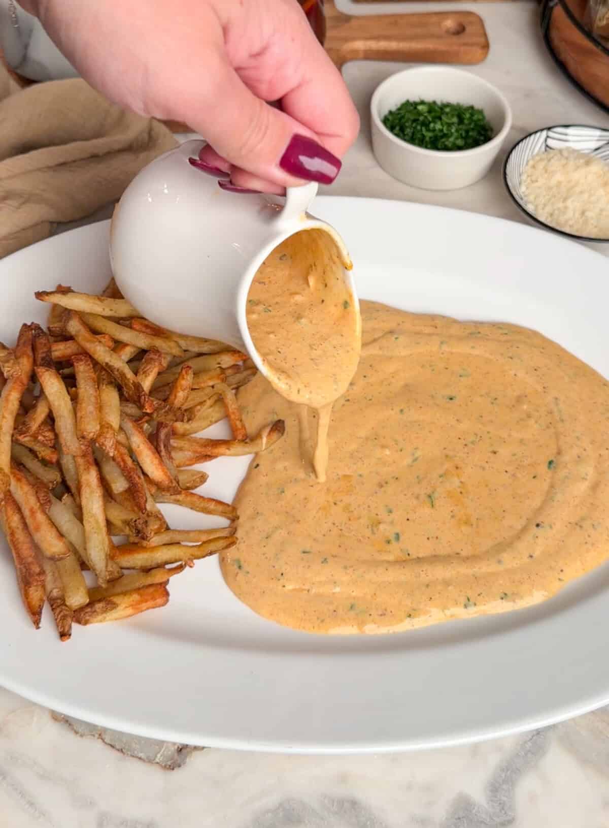pouring the garlic parmesan sauce in the plate