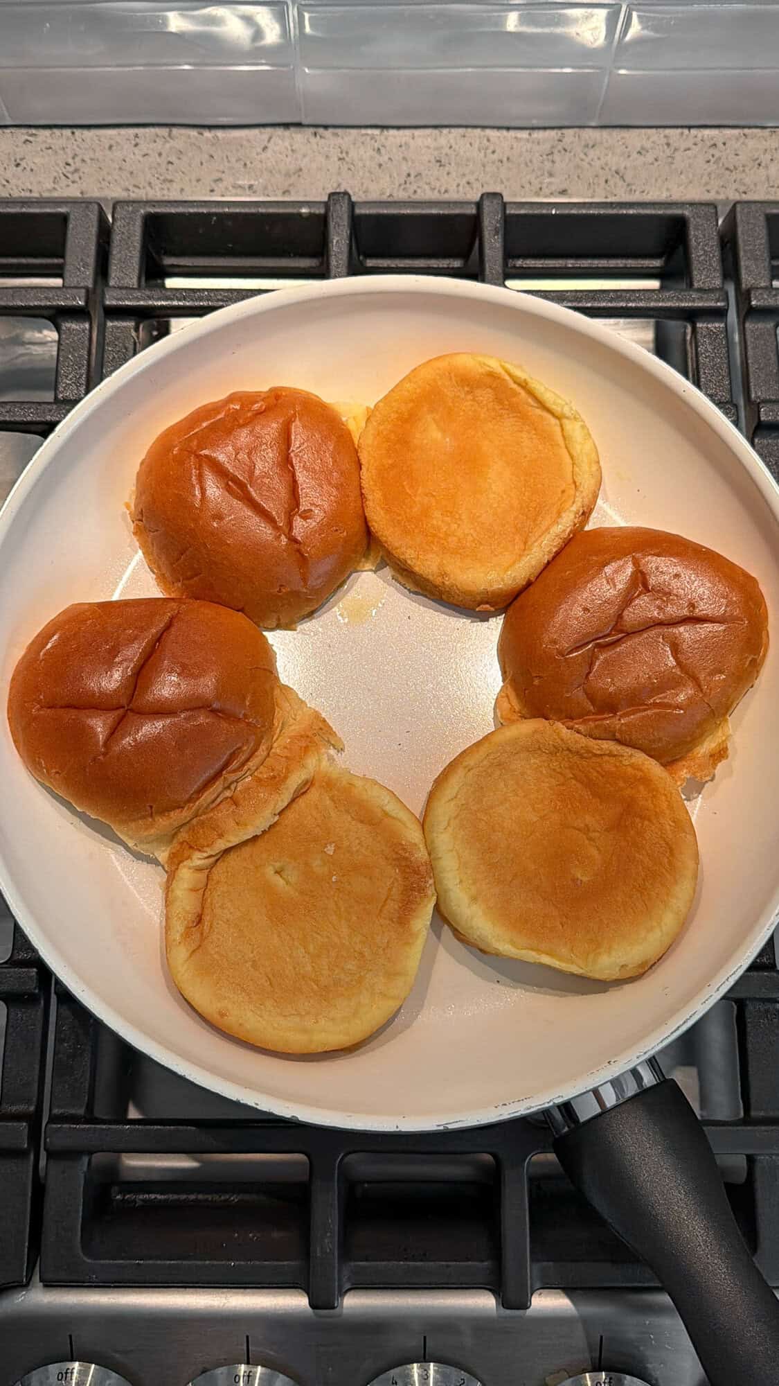toasting buttered brioche buns in a pan