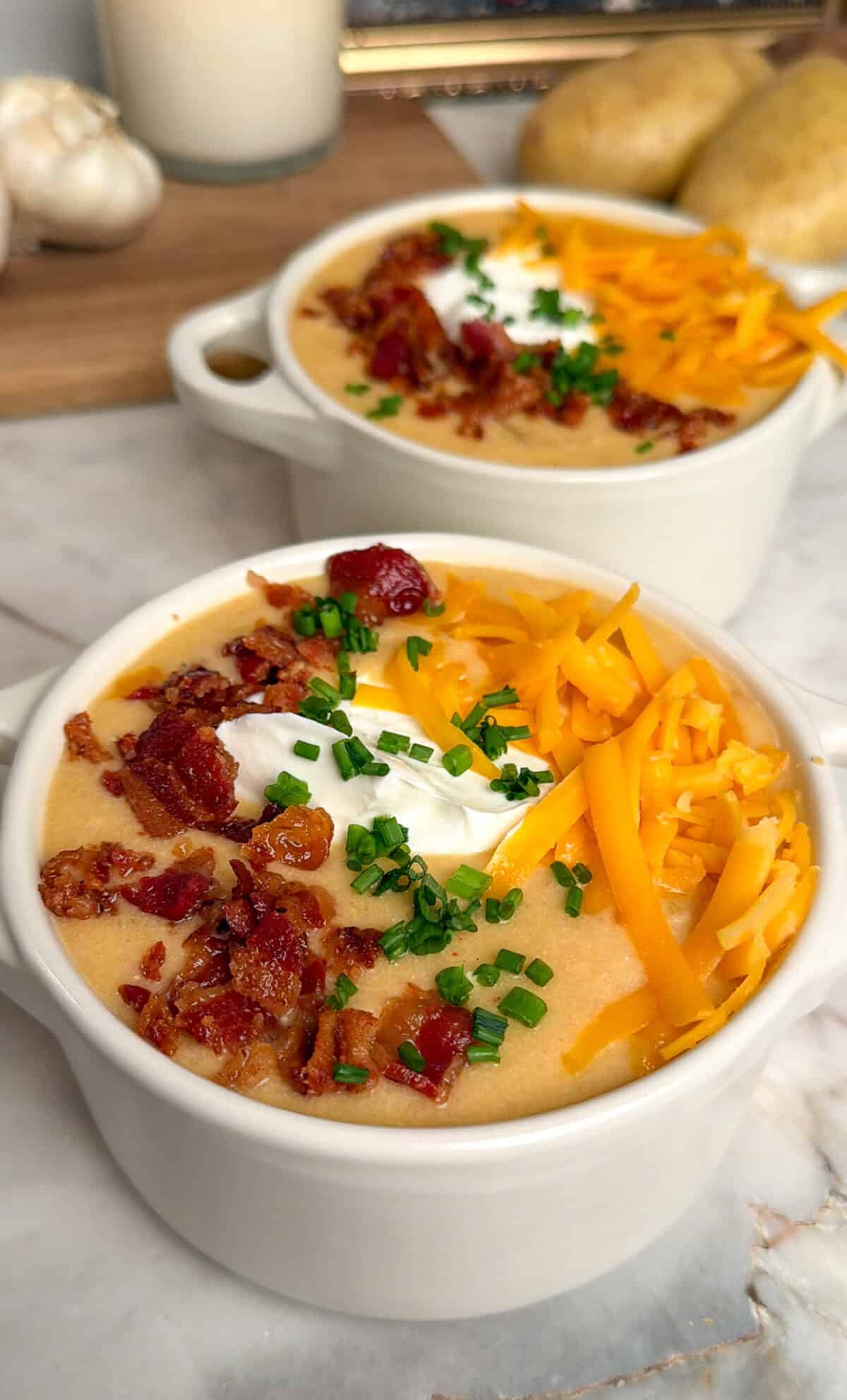 cheesy potato soup in a bowl with bacon, cheddar, sour cream, and chives
