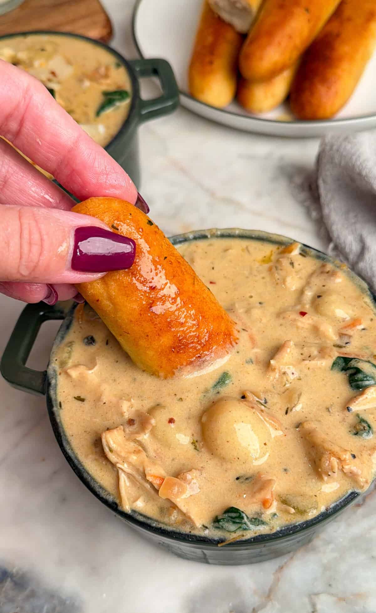 chicken gnocchi soup with breadsticks dipped in